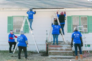 Langley employees in matching blue shirts replace soffett on a home while standing on ladders.